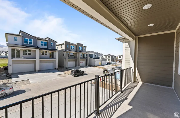 Covered outdoor balcony featuring a concrete floor, black metal railing, and recessed lighting