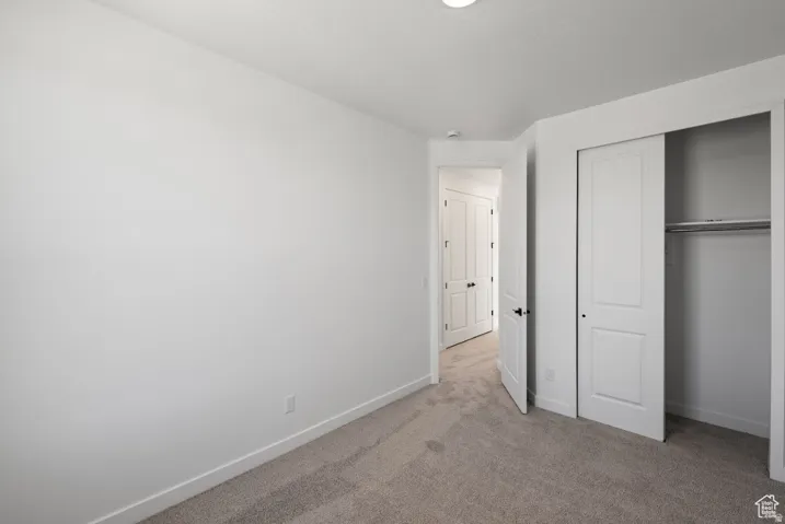Neutral tone wall paint, carpet flooring, baseboard trim, white interior doors, and a built-in closet with sliding doors