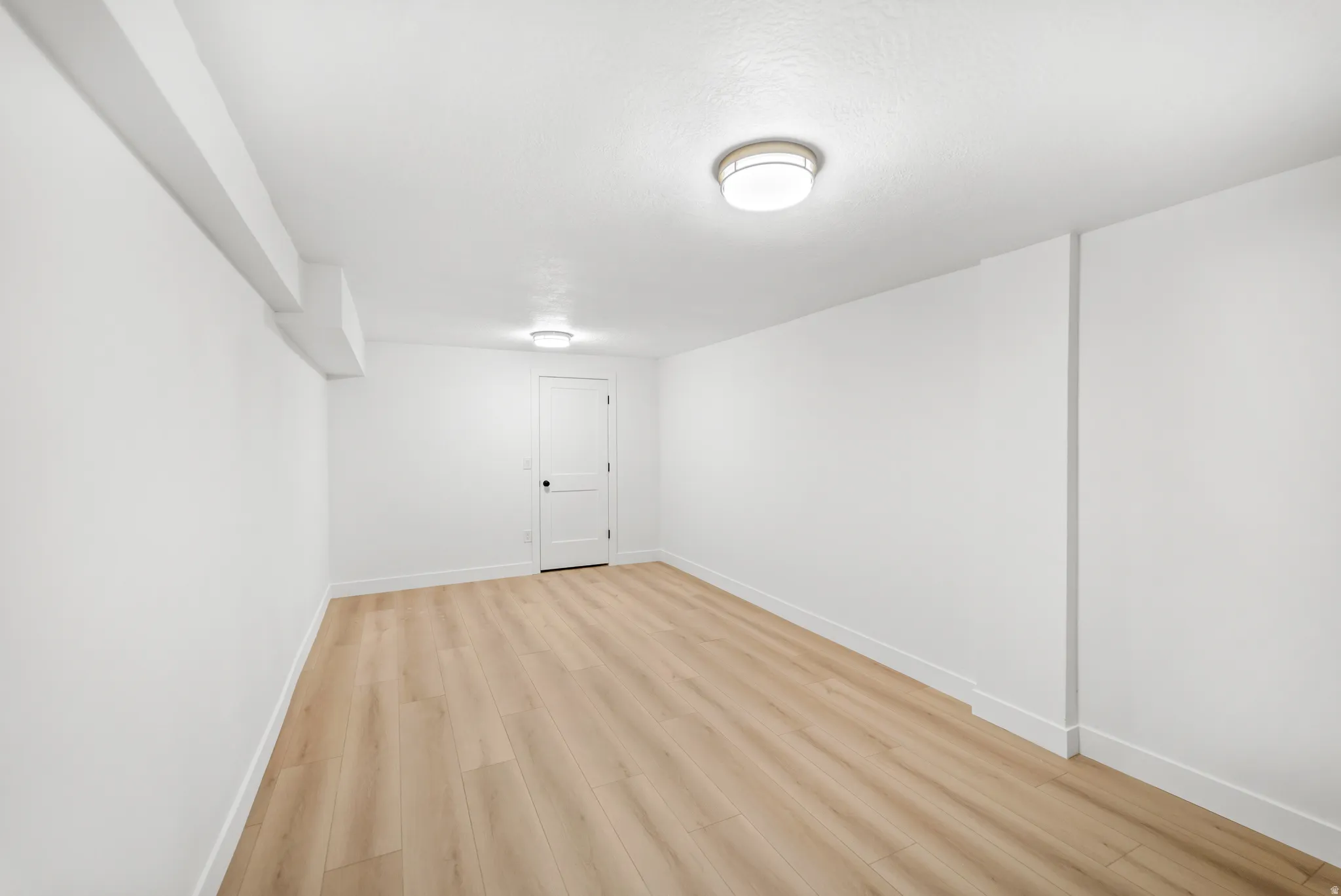 Light wood-finish flooring with white baseboards and walls