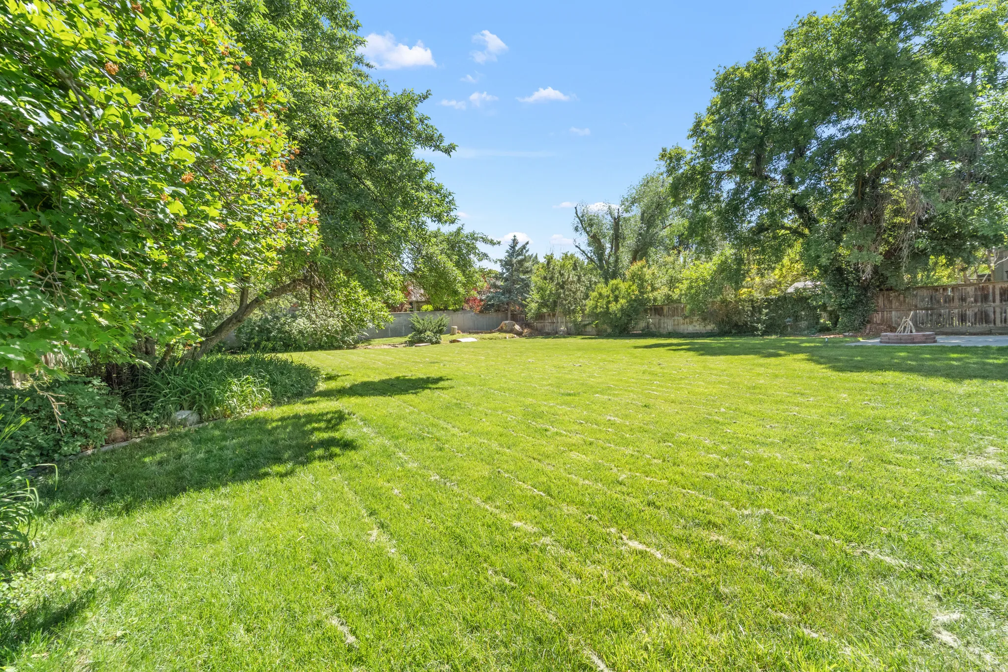 Expansive green lawn surrounded by mature trees, providing natural shade