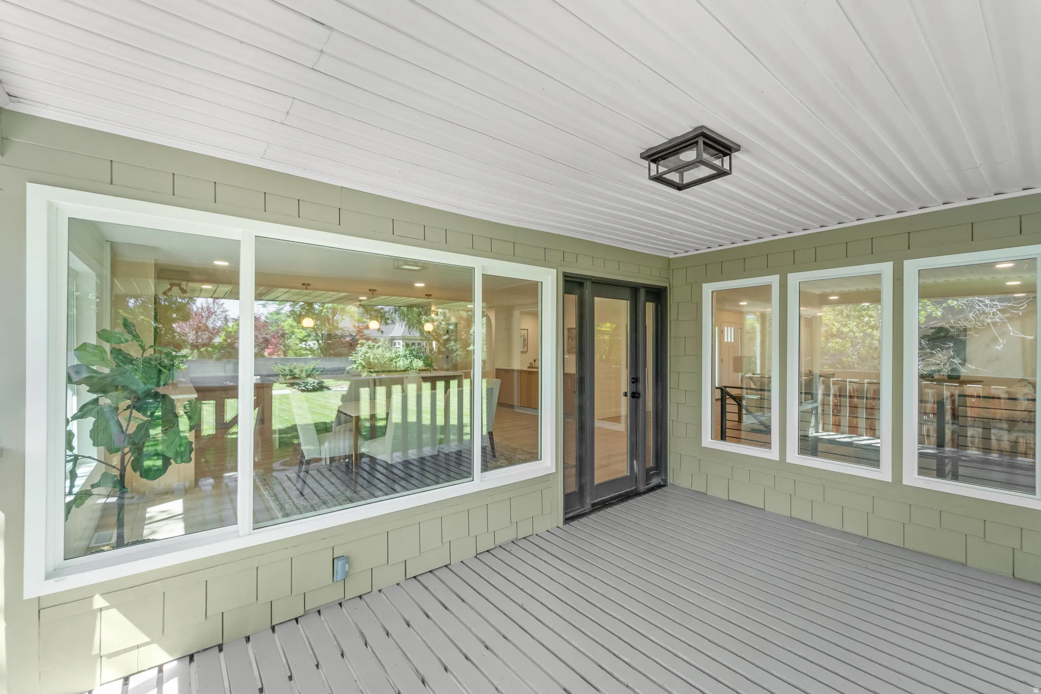 Covered porch with composite decking, shingle siding, and a beadboard ceiling
