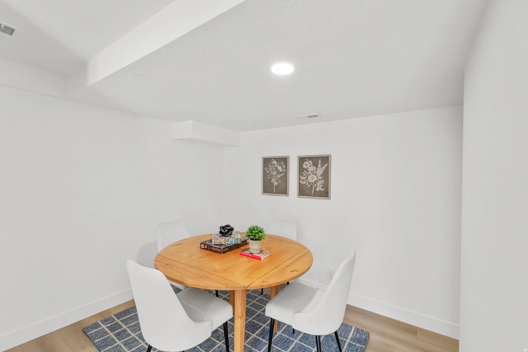 Recessed lighting illuminating a spacious room with white walls and wood-finish flooring
