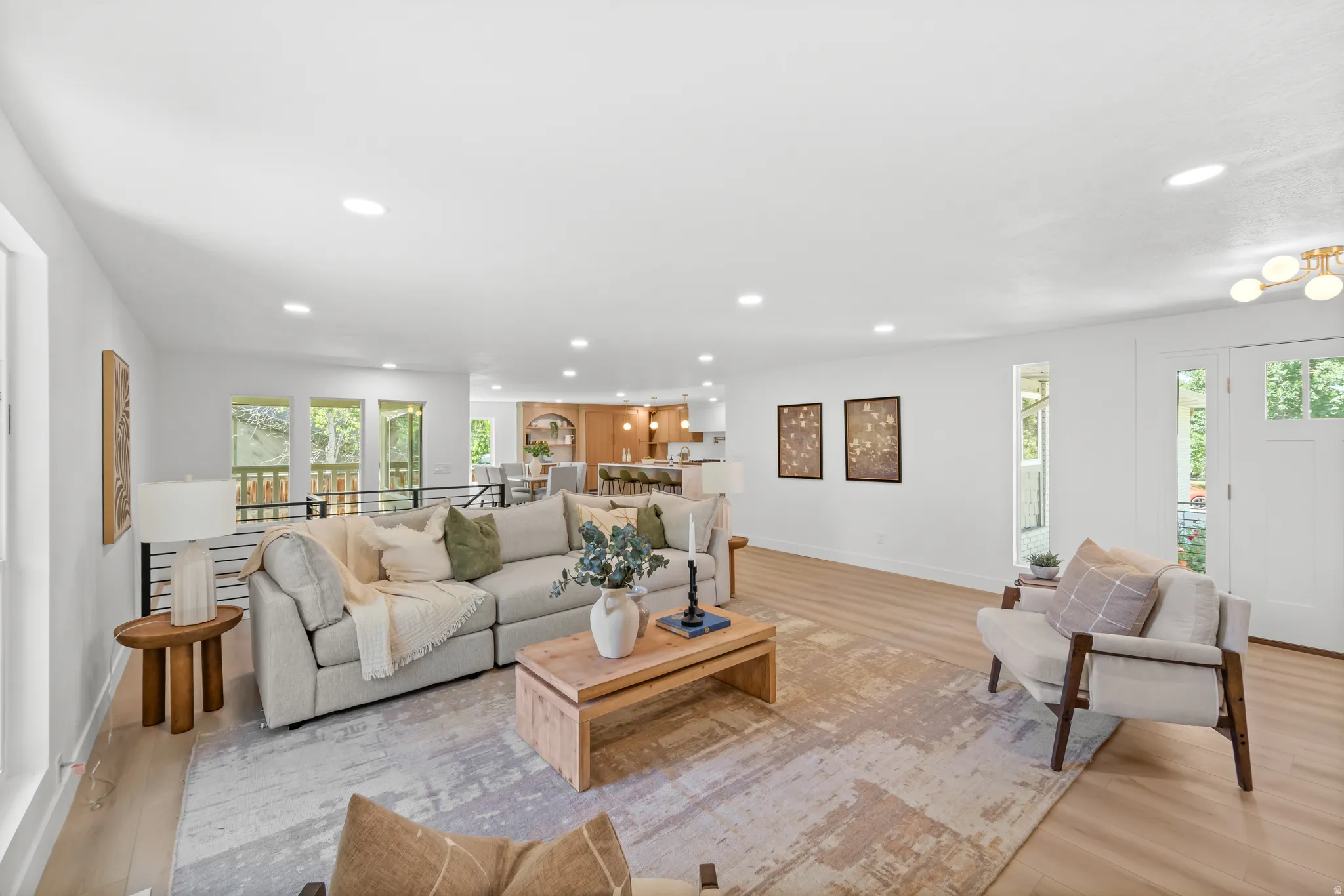 Expansive living area featuring light wood-finish flooring, recessed lighting, and white walls