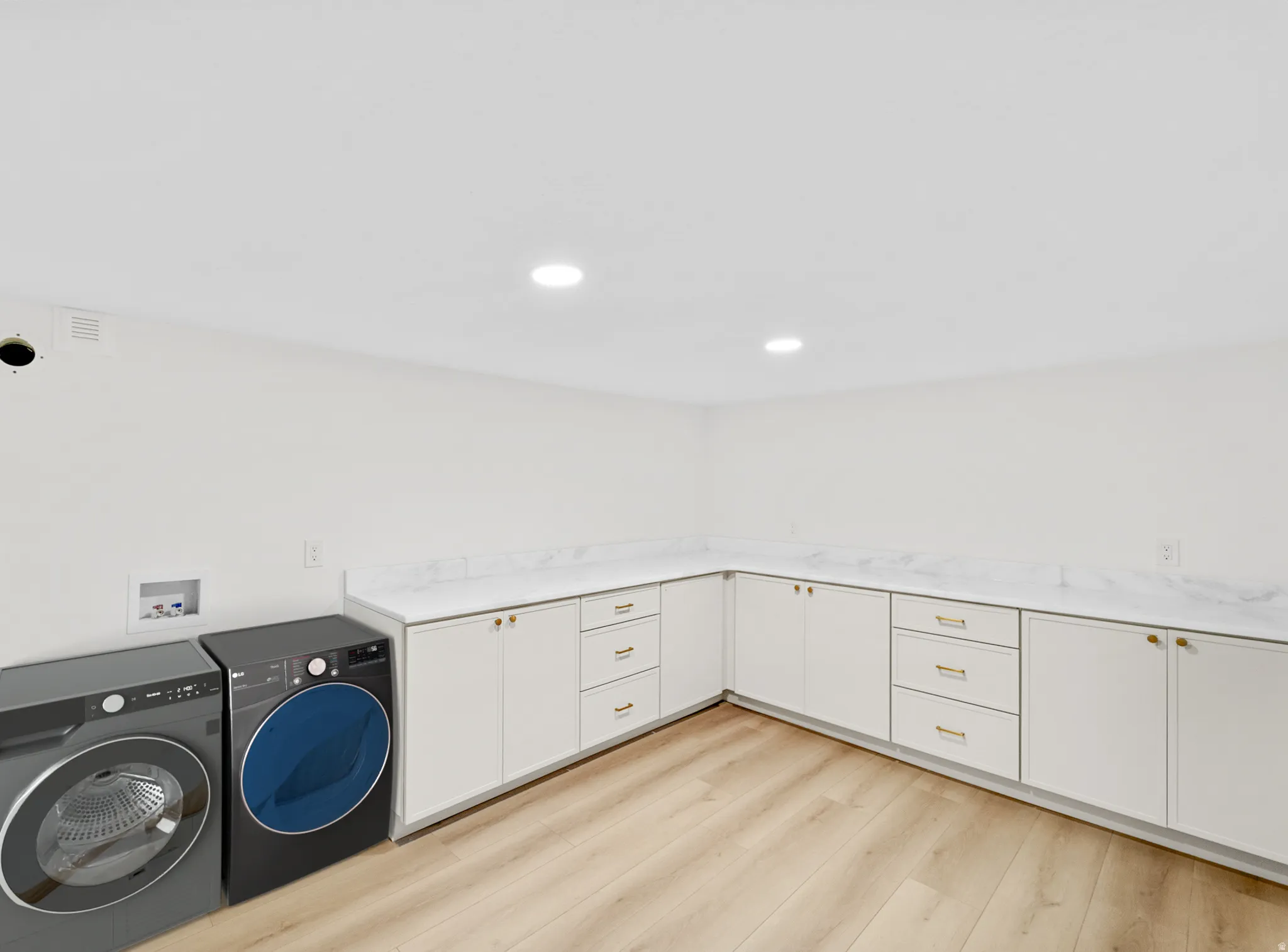 Laundry area featuring white cabinetry, light countertops, wood-finish flooring, recessed lighting, and ample counter space