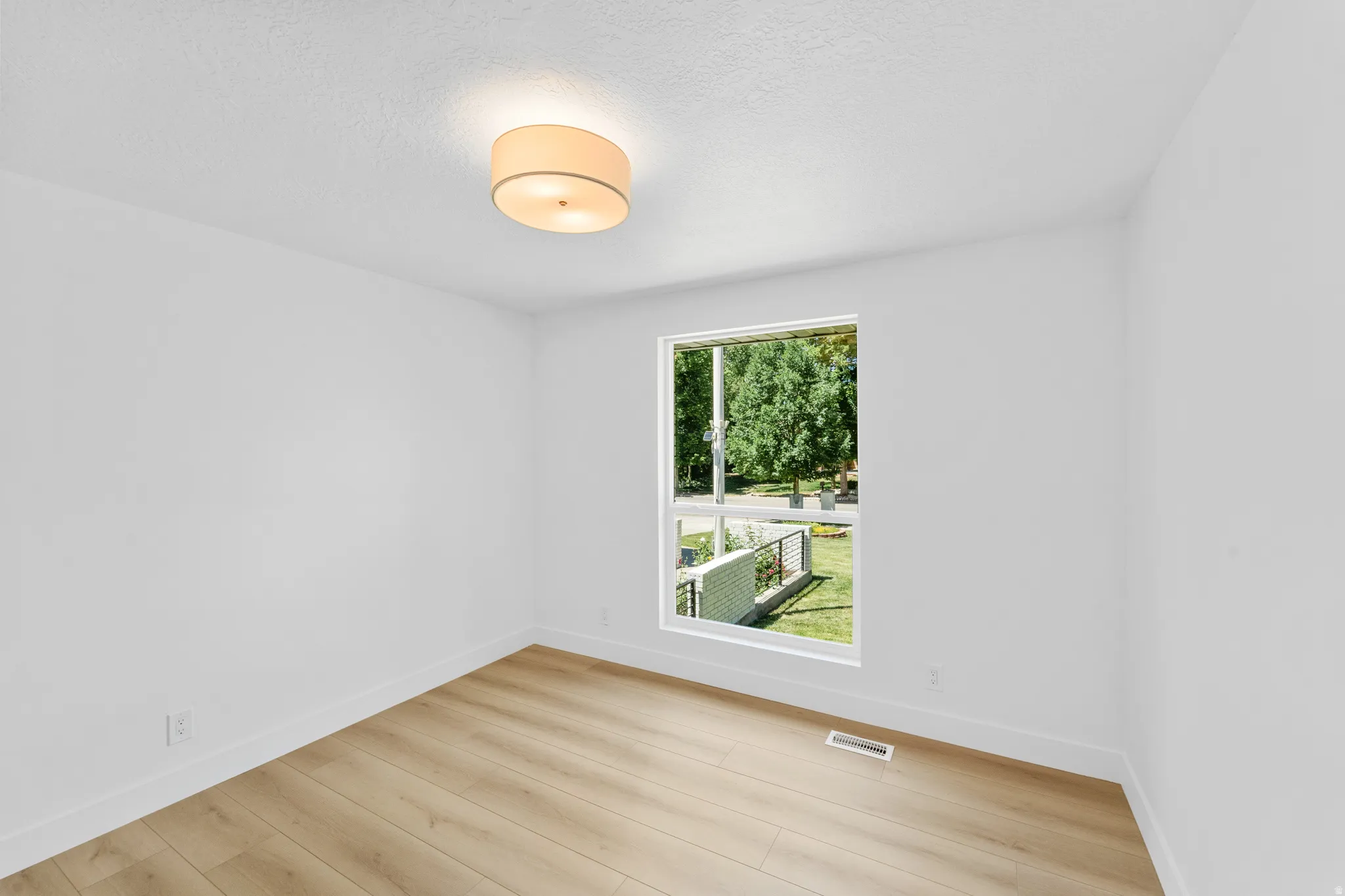 Bright room featuring wood-finish flooring, white baseboards, and a large window