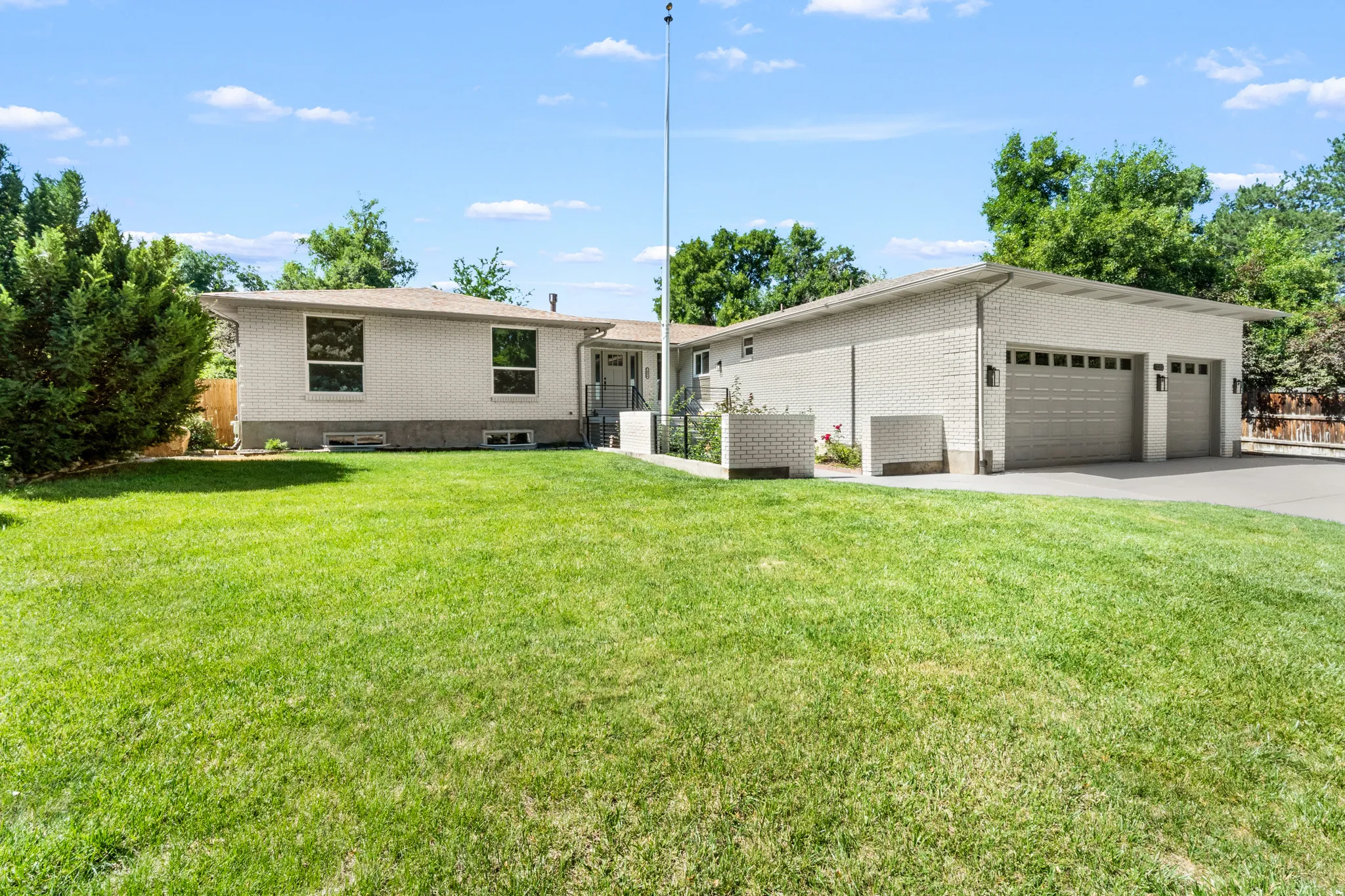 White brick exterior with a multi-car garage and a paved driveway
