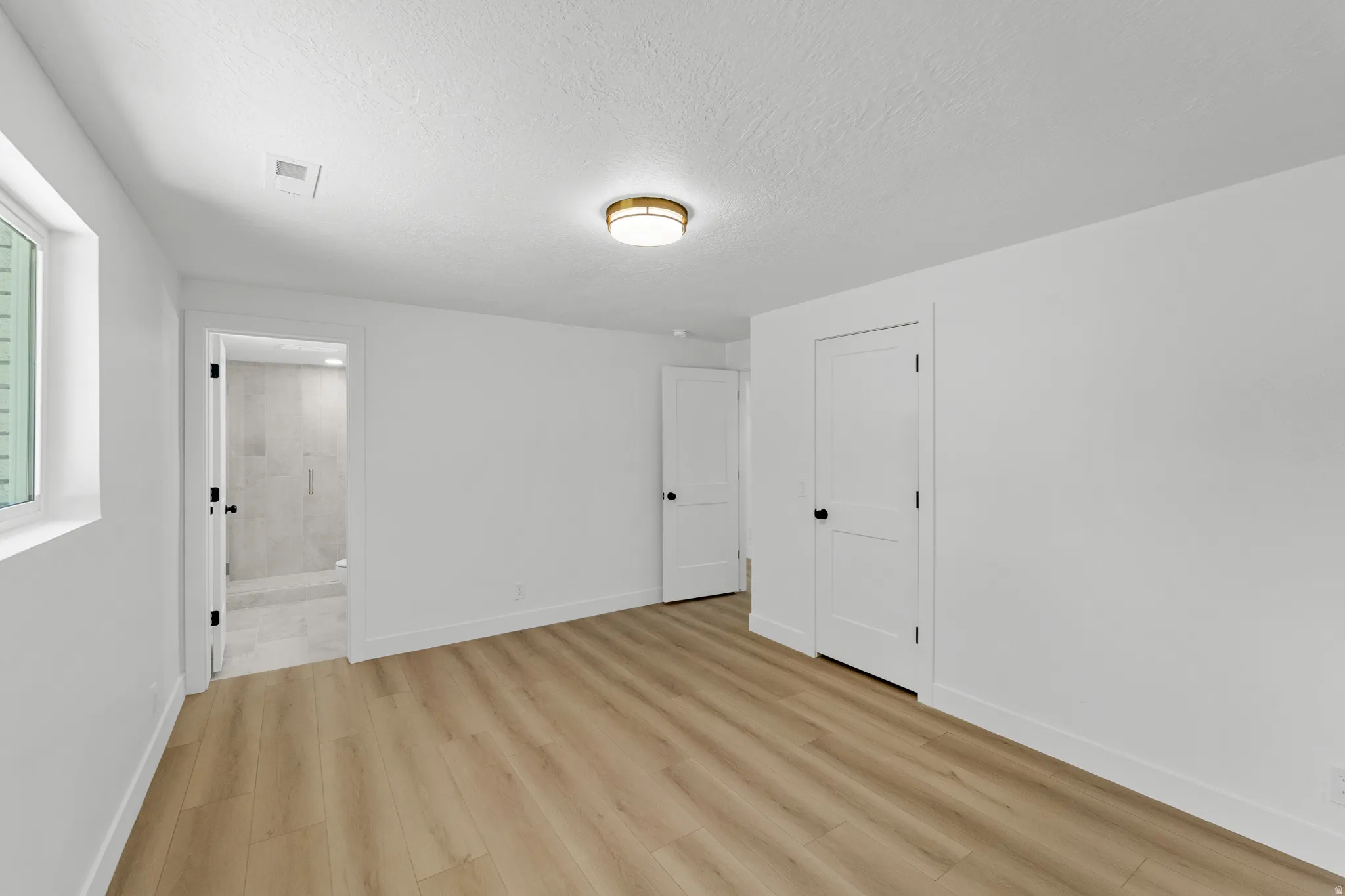 Room featuring light wood-finish flooring, white walls, and a window with a white frame