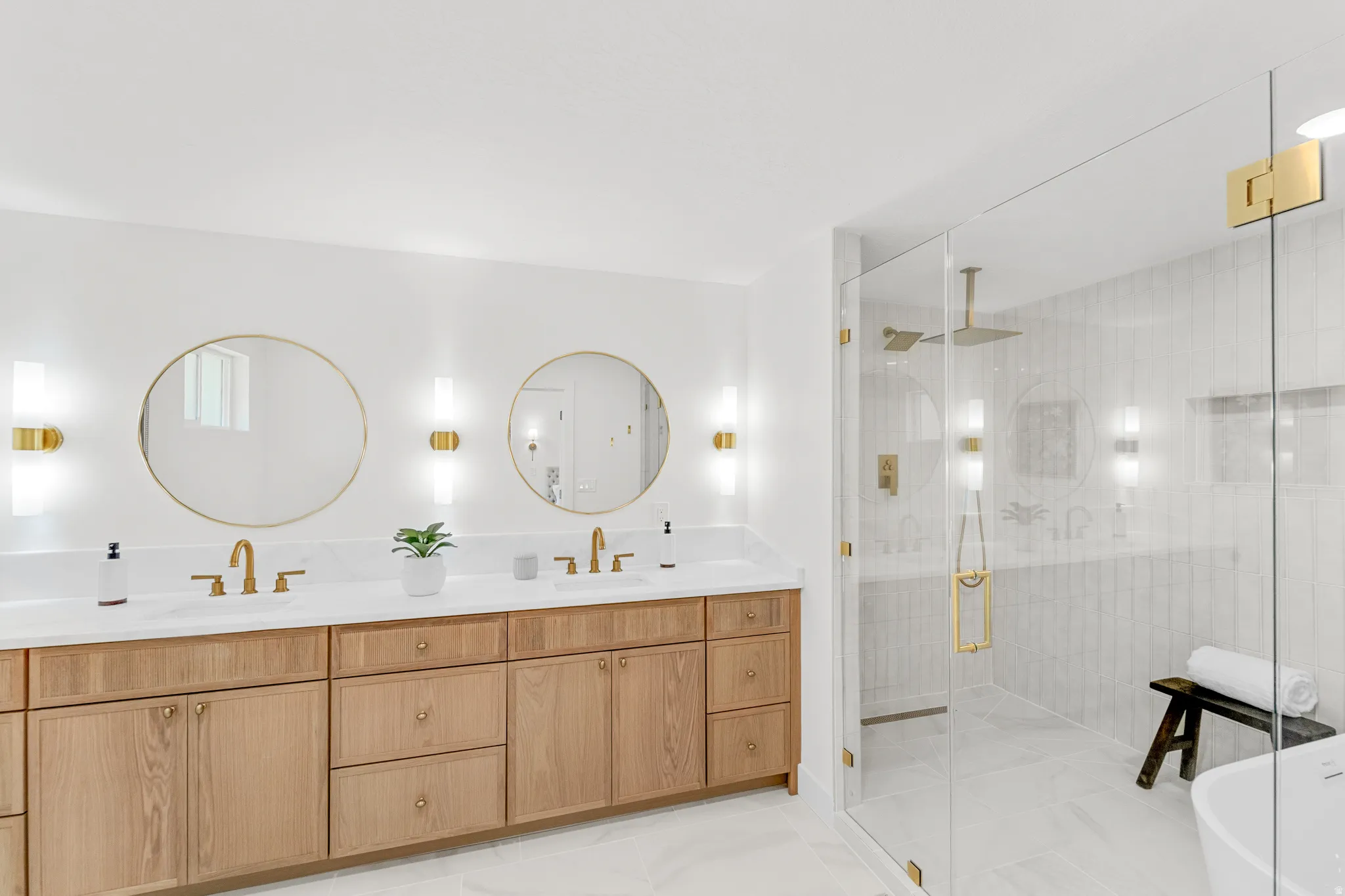 Double vanity featuring wood-finish cabinetry, white countertops, and gold-finish fixtures
