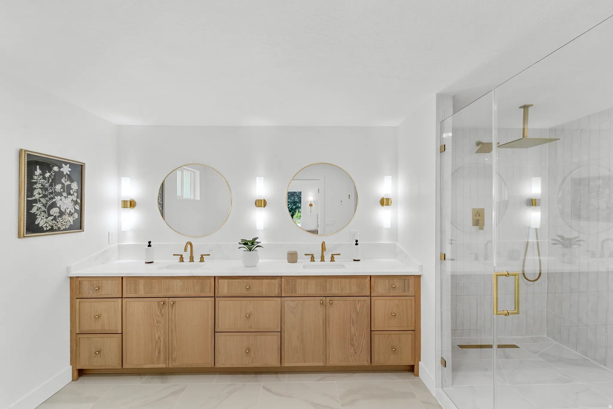 Dual vanity with wood cabinetry, white countertops, and gold-finish fixtures
