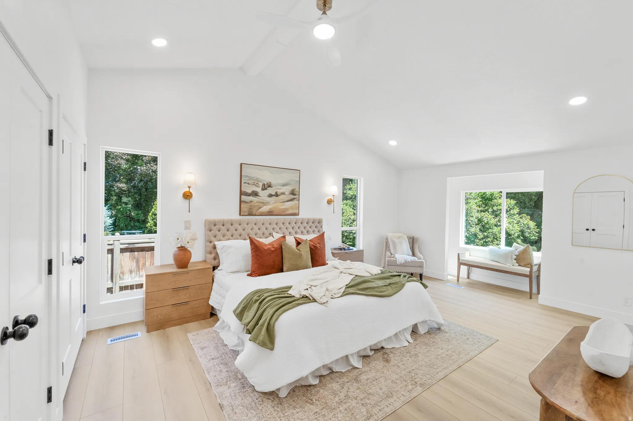 Spacious bedroom featuring vaulted ceilings, recessed lighting, a ceiling fan, light wood-finish flooring, and multiple windows