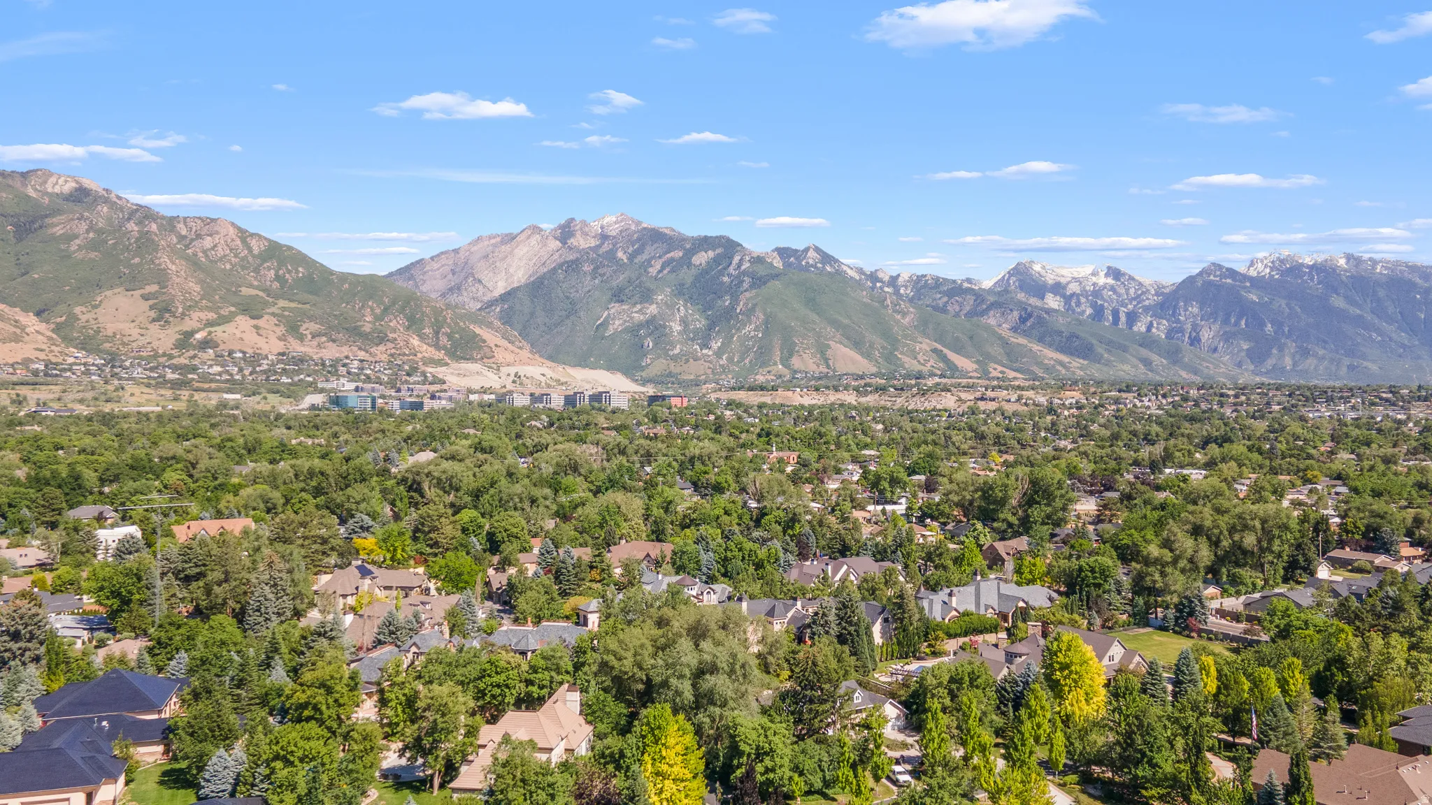Expansive aerial perspective showcasing a residential area set against a backdrop of prominent mountains