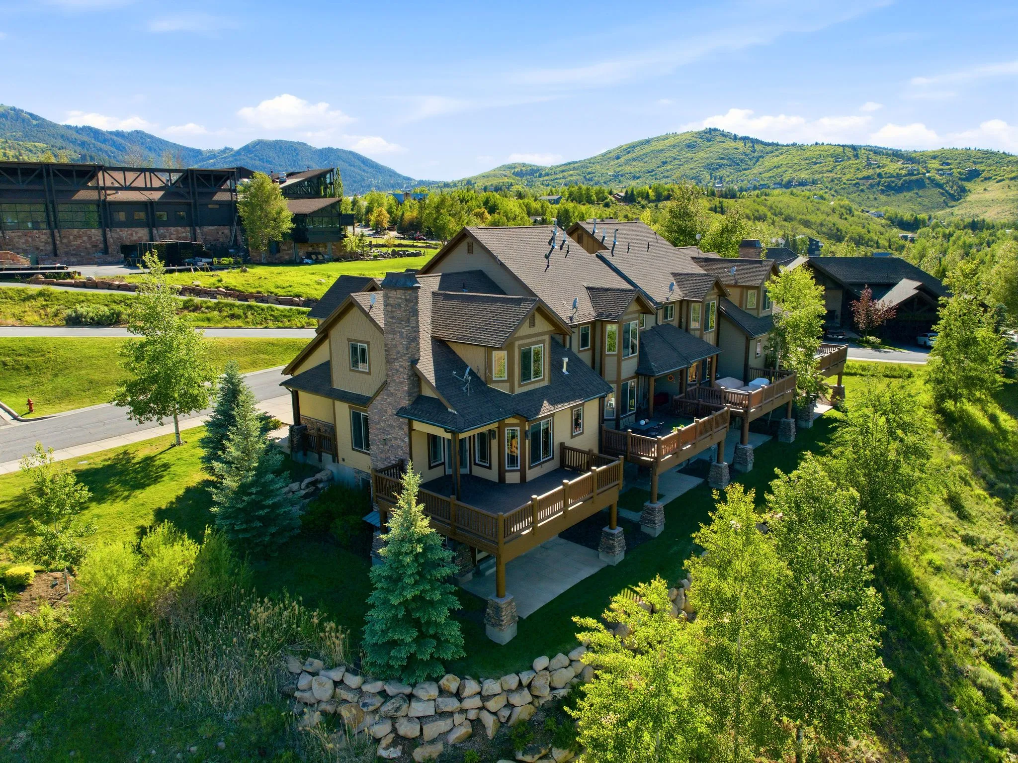 Multi-level residence featuring a stone chimney, multiple outdoor decks, and a prominent stone retaining wall