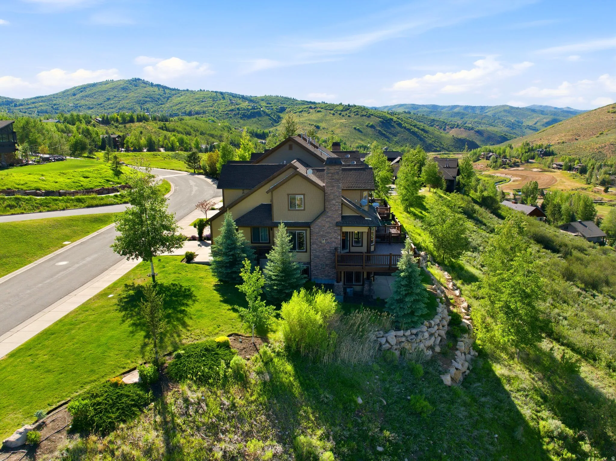 Contemporary residence with a multi-level design, featuring a stone chimney and expansive outdoor decking