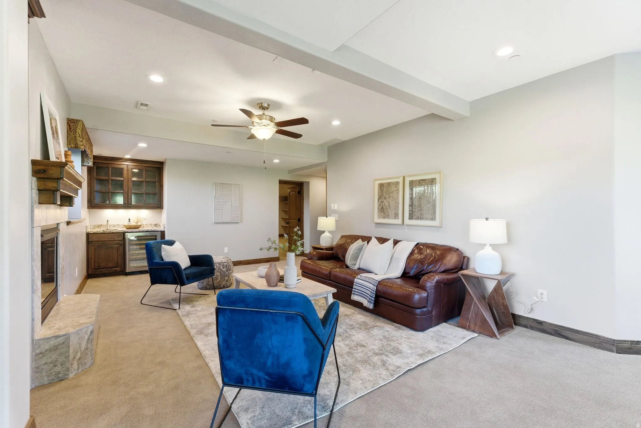 Carpeted living area featuring a built-in wet bar with wood cabinetry, a beverage refrigerator, and a recessed fireplace with a stone hearth