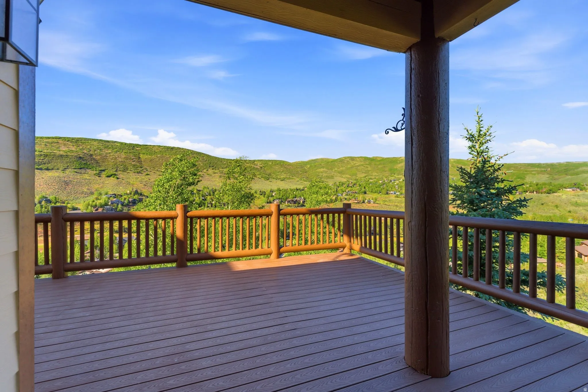 Expansive outdoor deck featuring wood-finish composite decking, log railing, and a large log support column