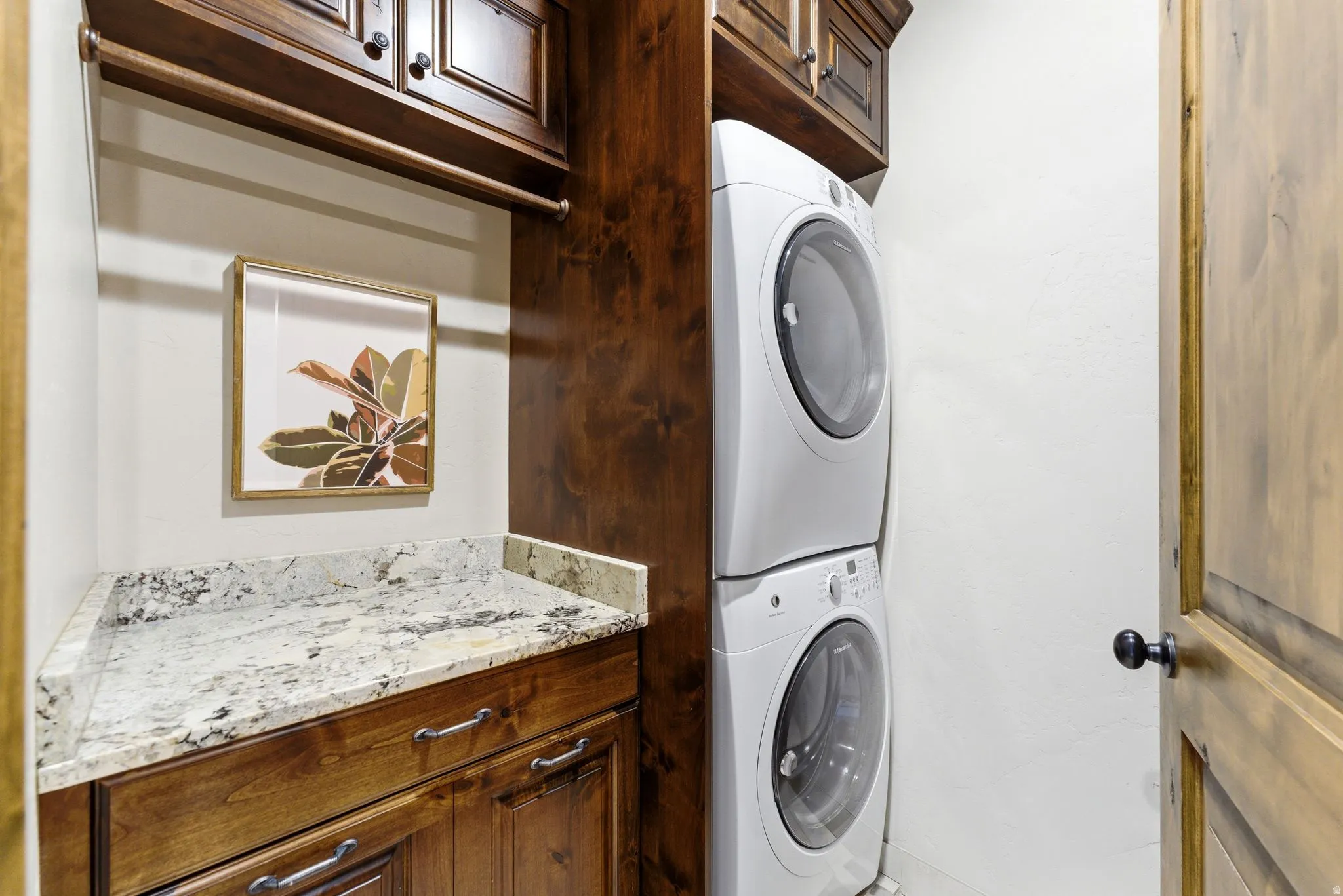 Integrated laundry area featuring wood cabinetry, a granite-finish countertop, and a built-in hanging rod