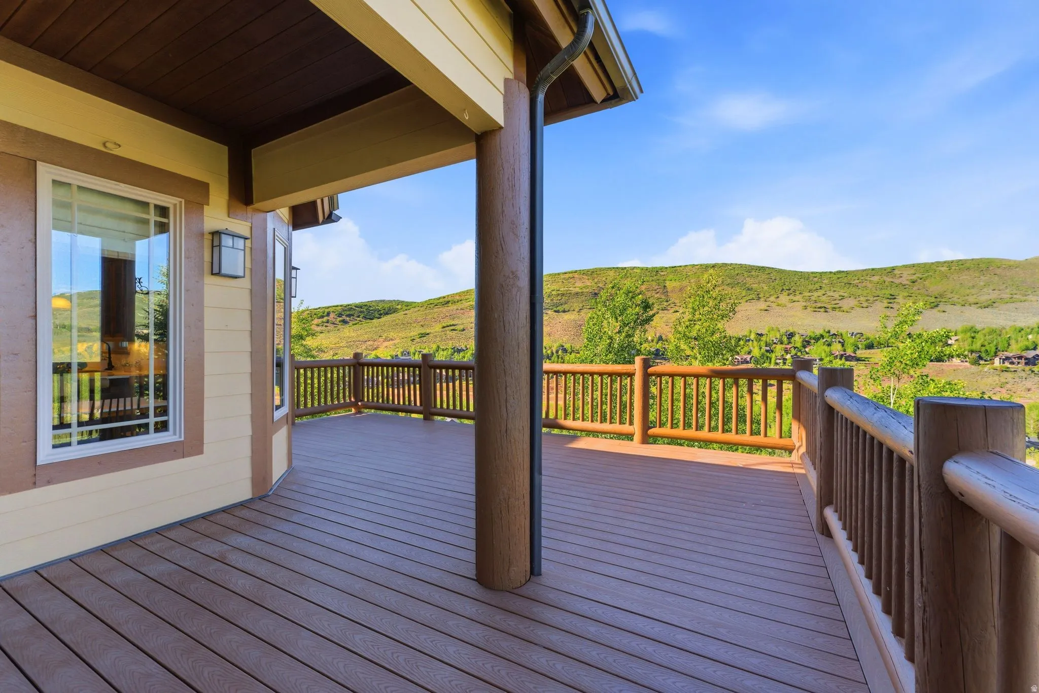 Expansive outdoor deck featuring wood-finish flooring and log-style railings