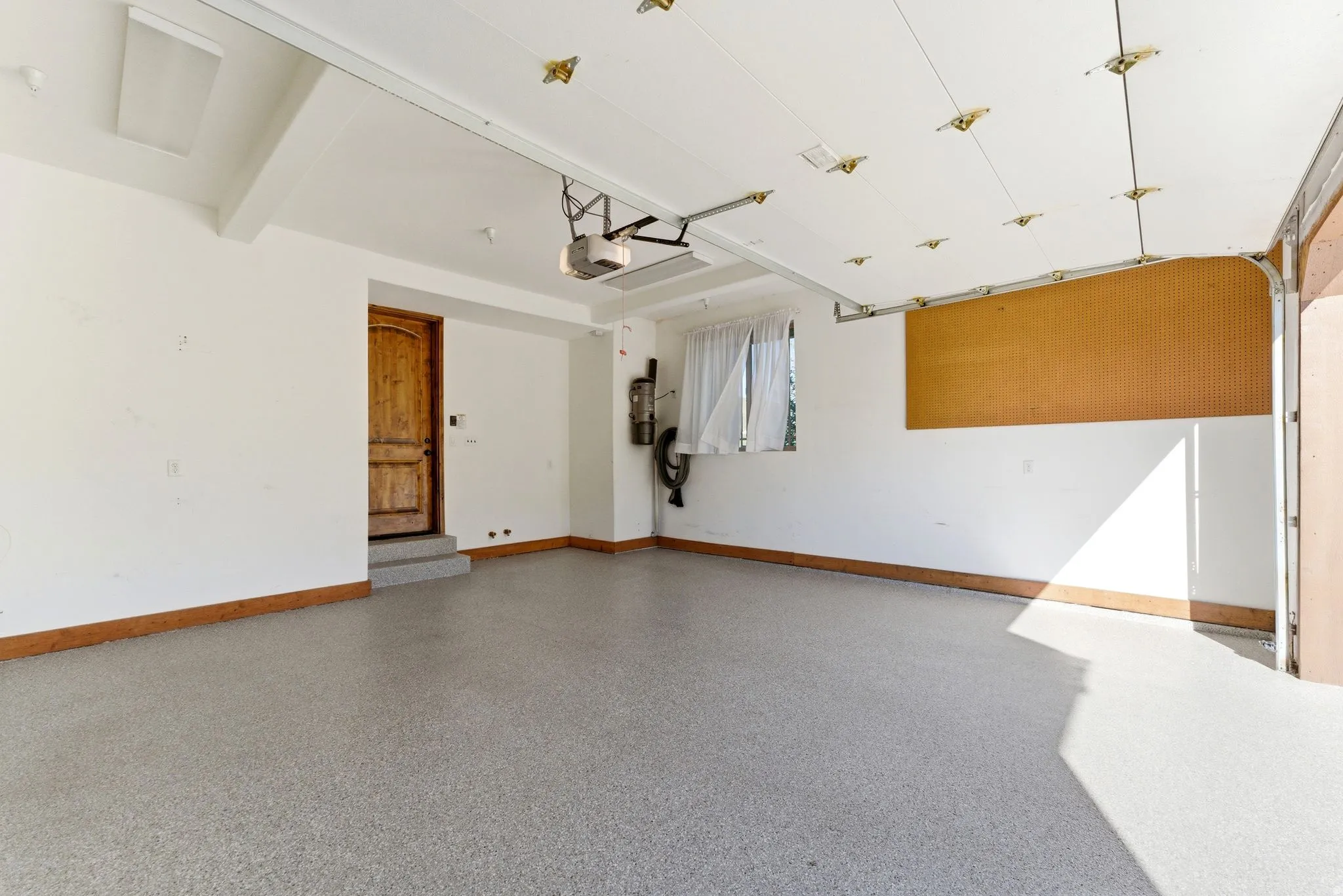 Spacious garage featuring epoxy flooring, a paneled wood interior door, and an automatic garage door opener