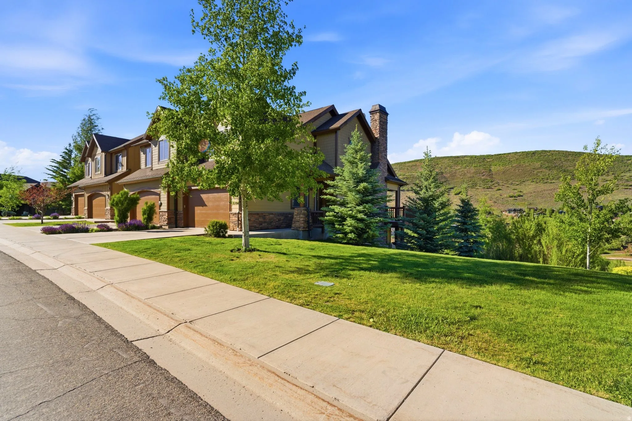 Multi-story residence featuring a combination of siding and stone veneer, multiple garage doors, and a prominent stone chimney