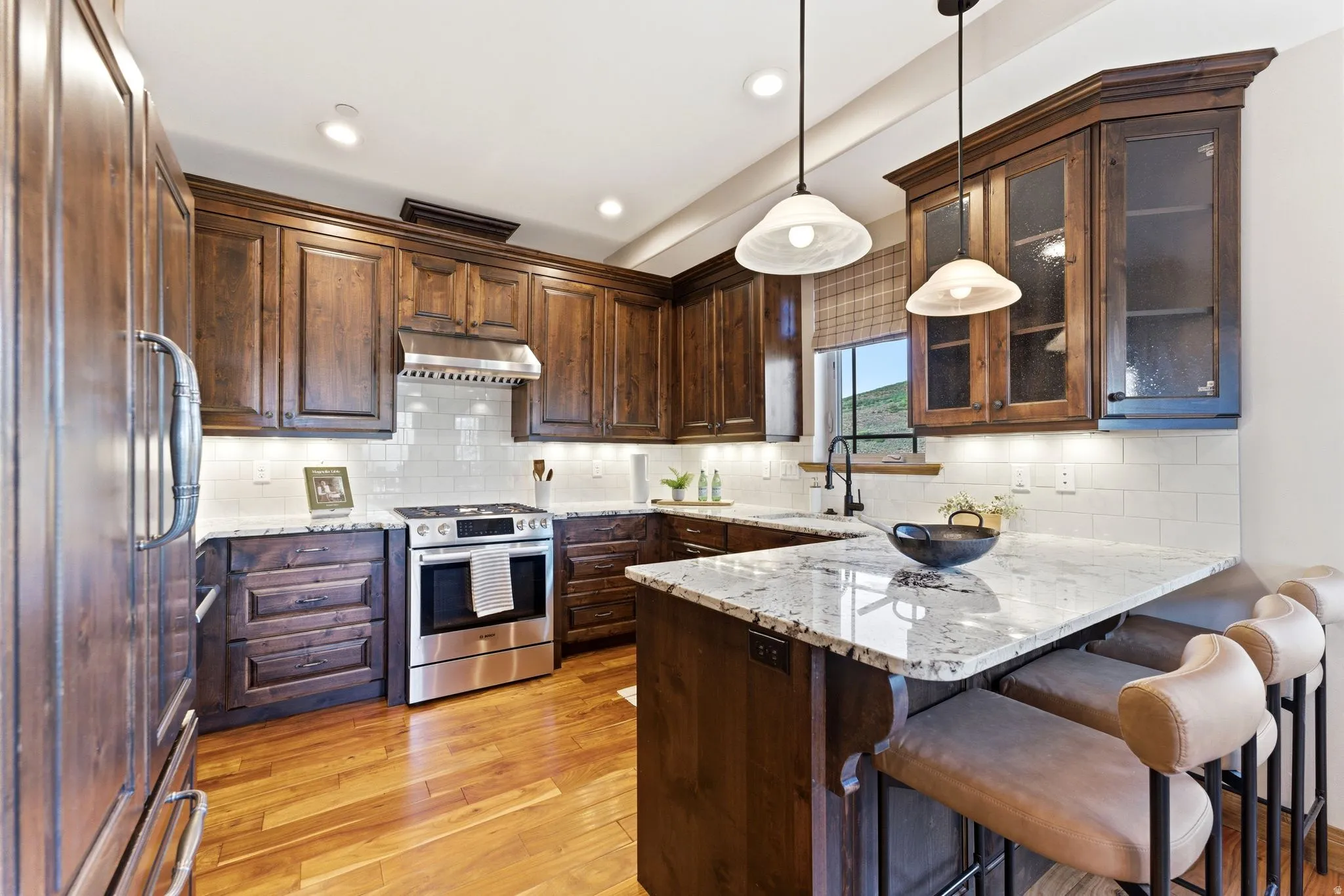 Kitchen featuring wood cabinetry, stainless steel appliances, a subway tile backsplash, and a large central island with seating