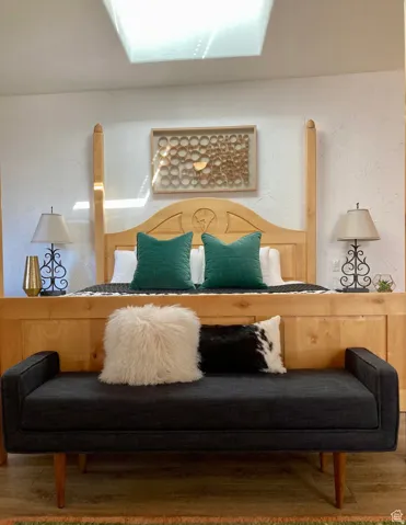 Recessed ceiling skylight above a light wood four-poster bed with carved headboard and integrated side panels