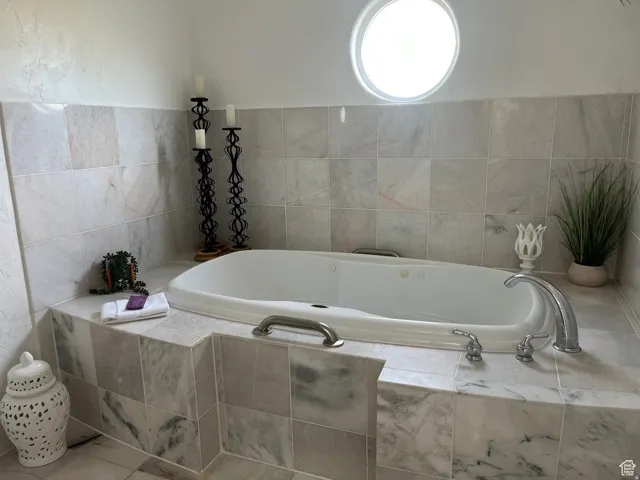 Soaking tub featuring a tiled surround and chrome fixtures