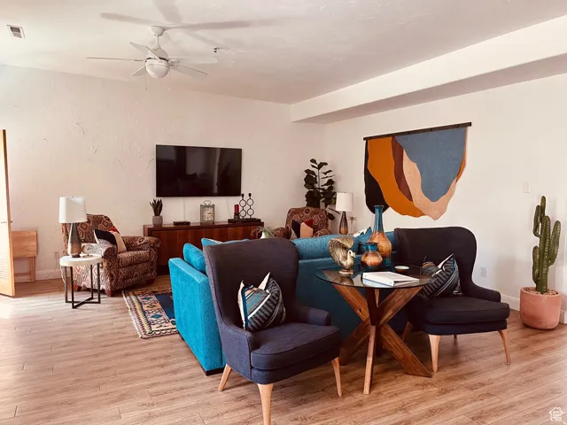 Expansive living area featuring wood-finish flooring, a textured white ceiling, and a ceiling fan
