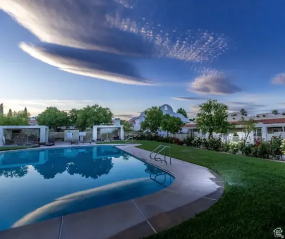 Community swimming pool with concrete decking, surrounding green lawn, and mature trees
