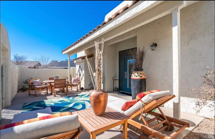 Private enclosed patio featuring stucco walls, a tiled roof overhang, and an exterior wall light fixture