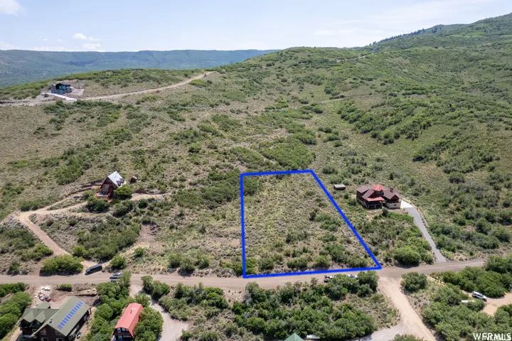 Elevated property parcel featuring natural shrubbery and a gentle slope