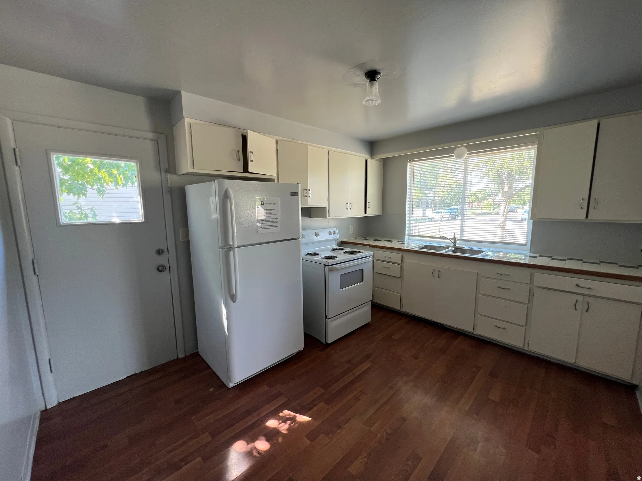 Functional kitchen featuring wood-finish flooring, white cabinetry, and a double-basin sink