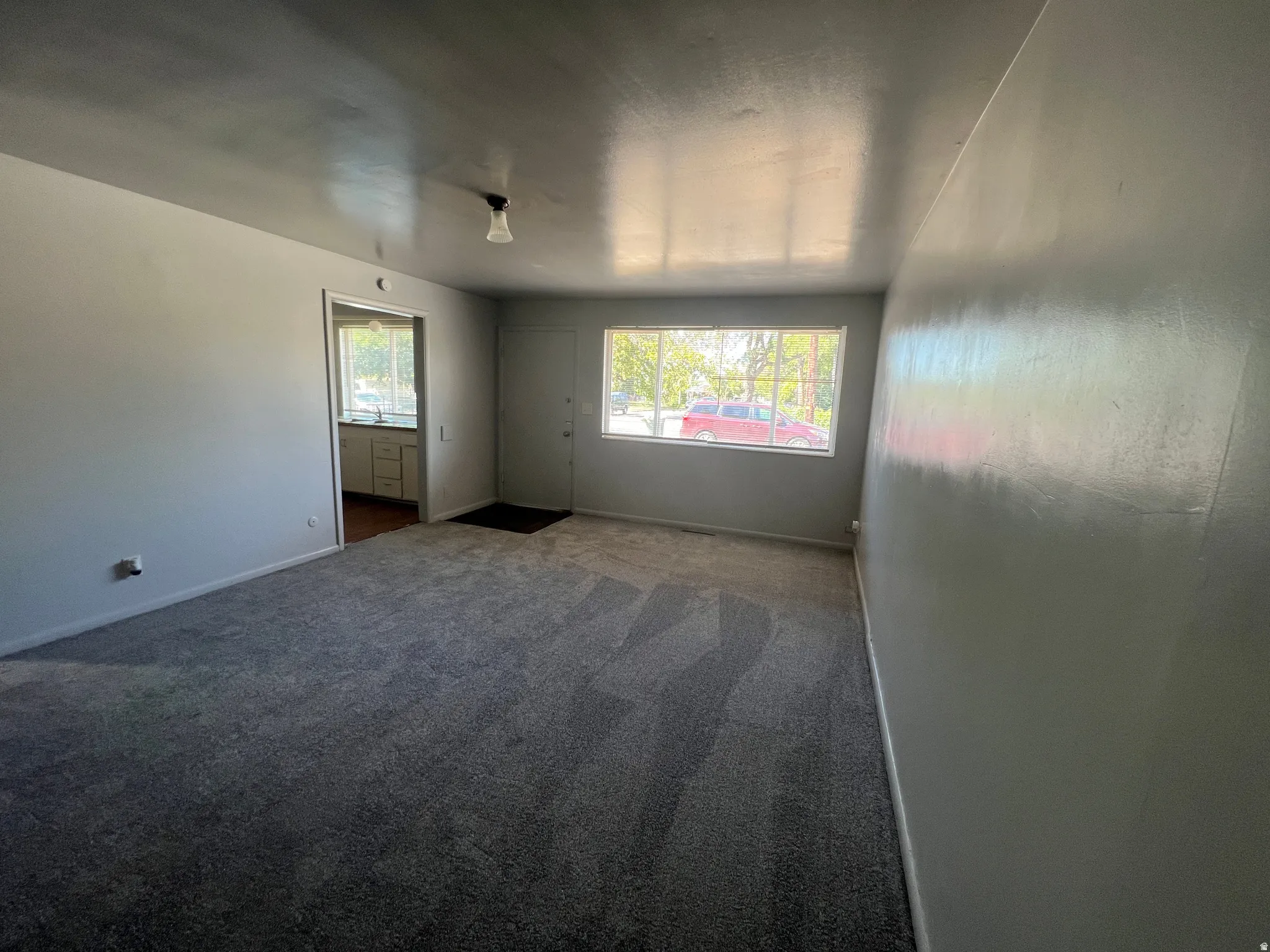 Spacious room featuring neutral grey carpeting and light-colored walls