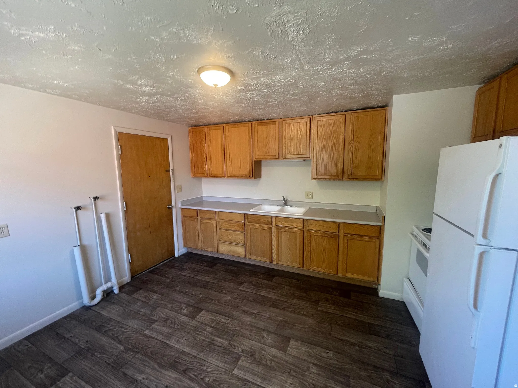 Kitchen featuring wood-finish flooring, light-toned cabinetry, and a white appliance suite