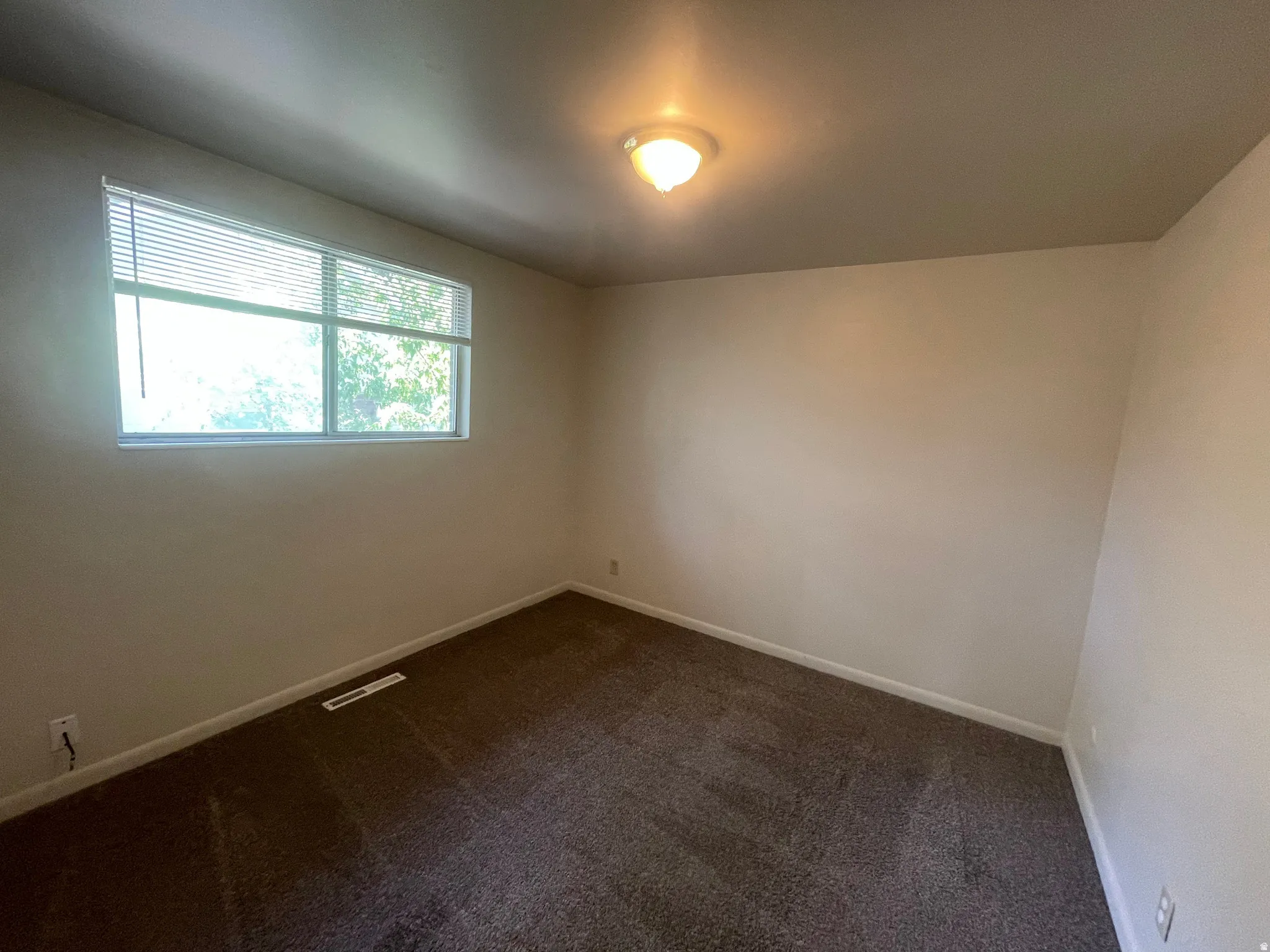 Spacious room featuring neutral wall tones and dark carpeting