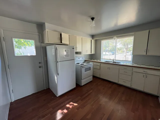 Functional kitchen featuring wood-finish flooring, white cabinetry, and a double-basin sink