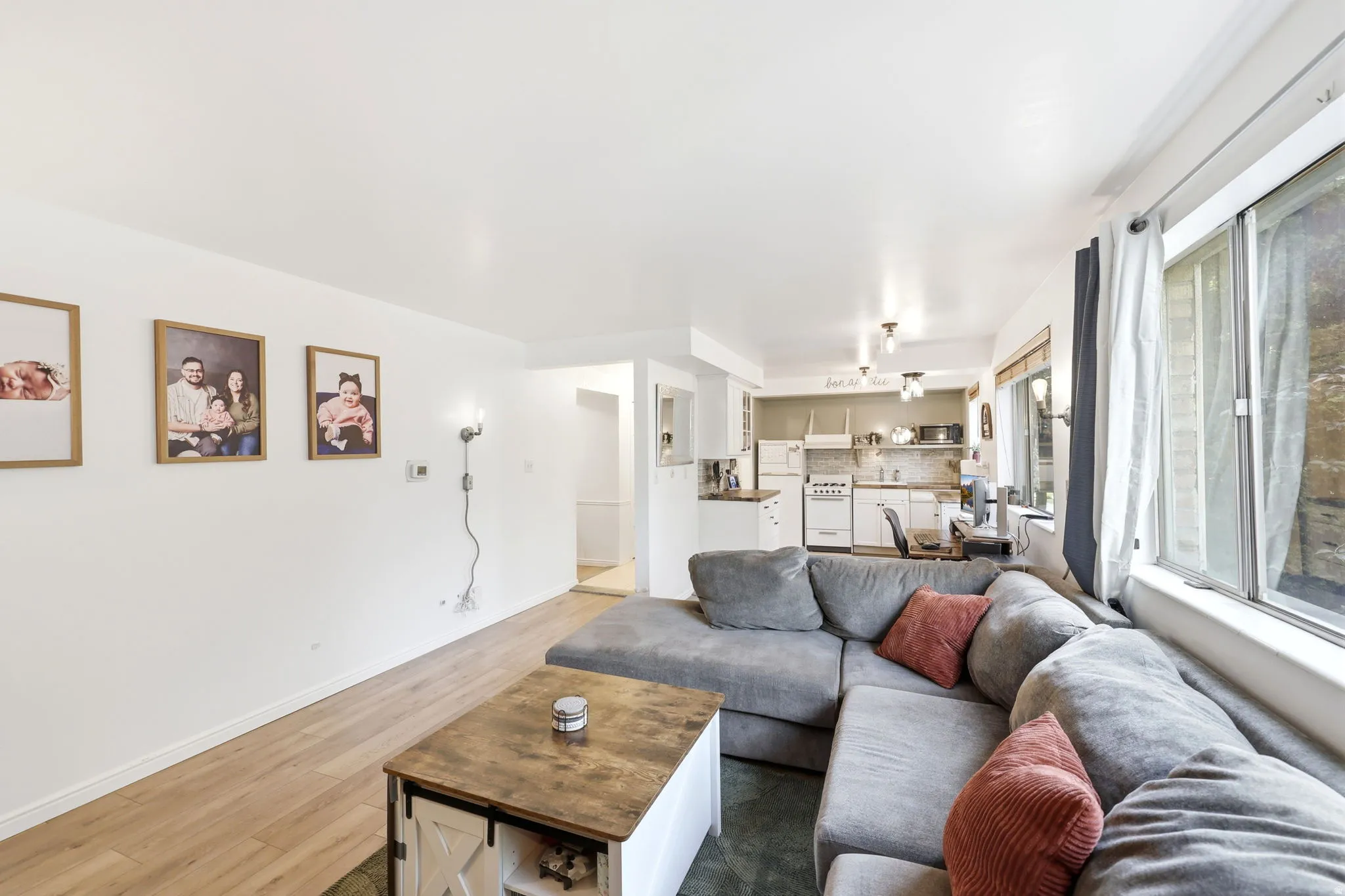 Open-concept living area featuring light wood-finish flooring, white baseboards, and a neutral wall color