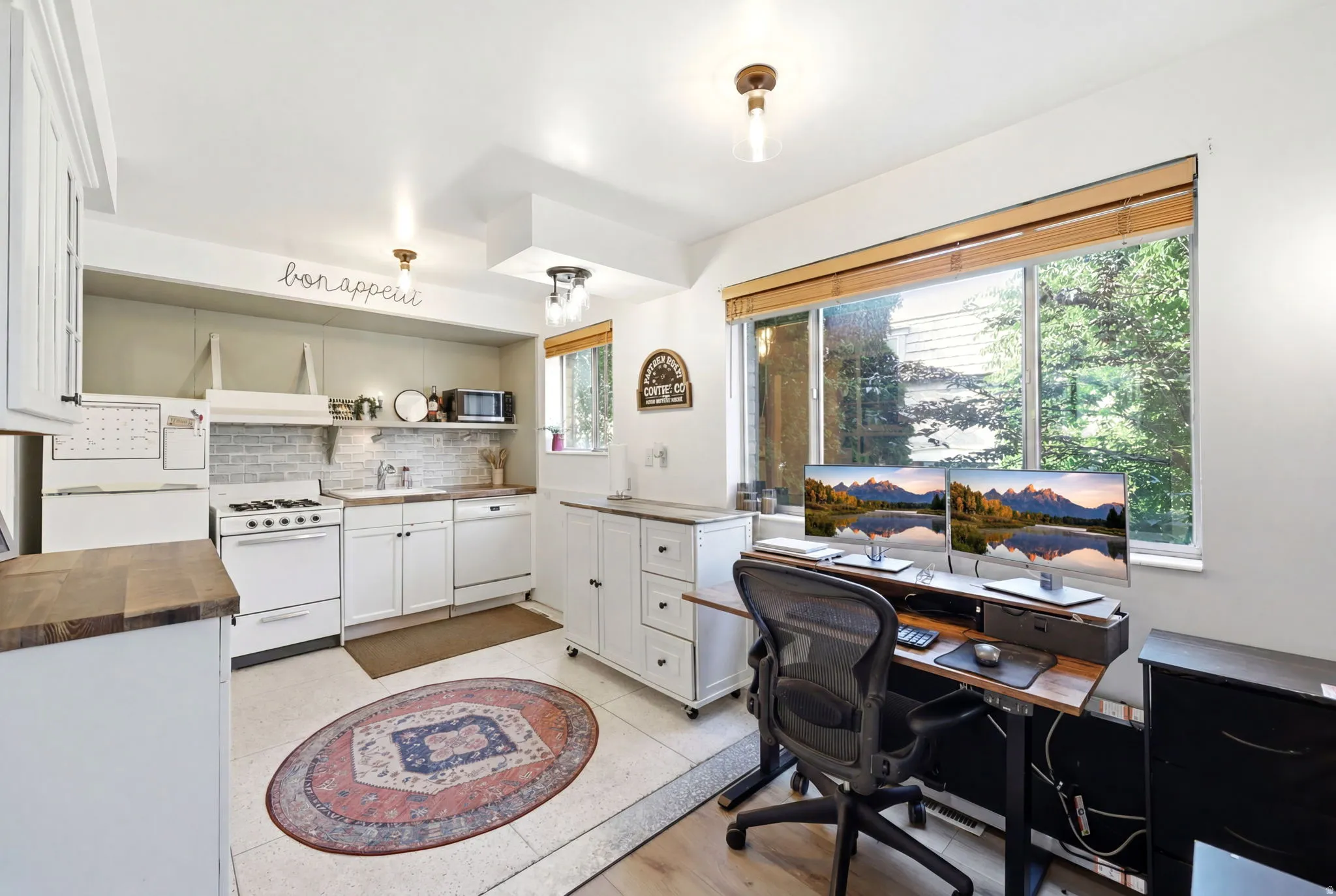 Integrated kitchen and office space featuring white cabinetry and appliances