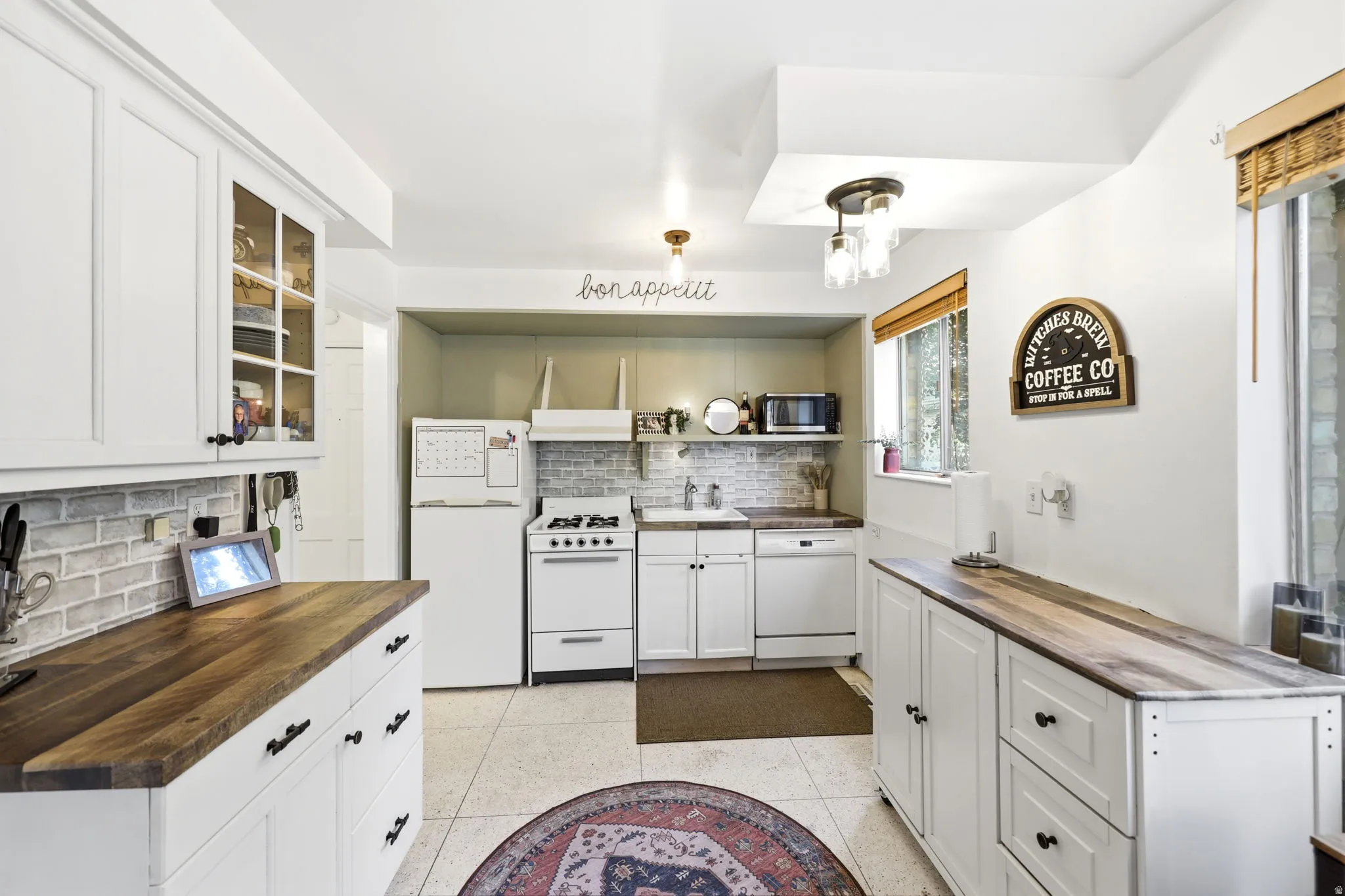 White cabinetry throughout featuring glass-front uppers and black hardware