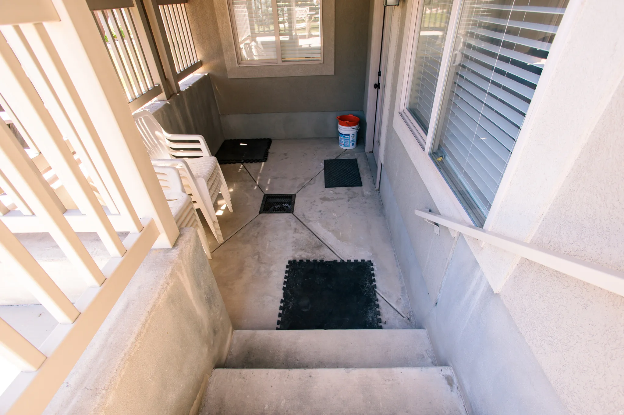 Concrete patio with a decorative stamped pattern, featuring a white railing and exterior stairs