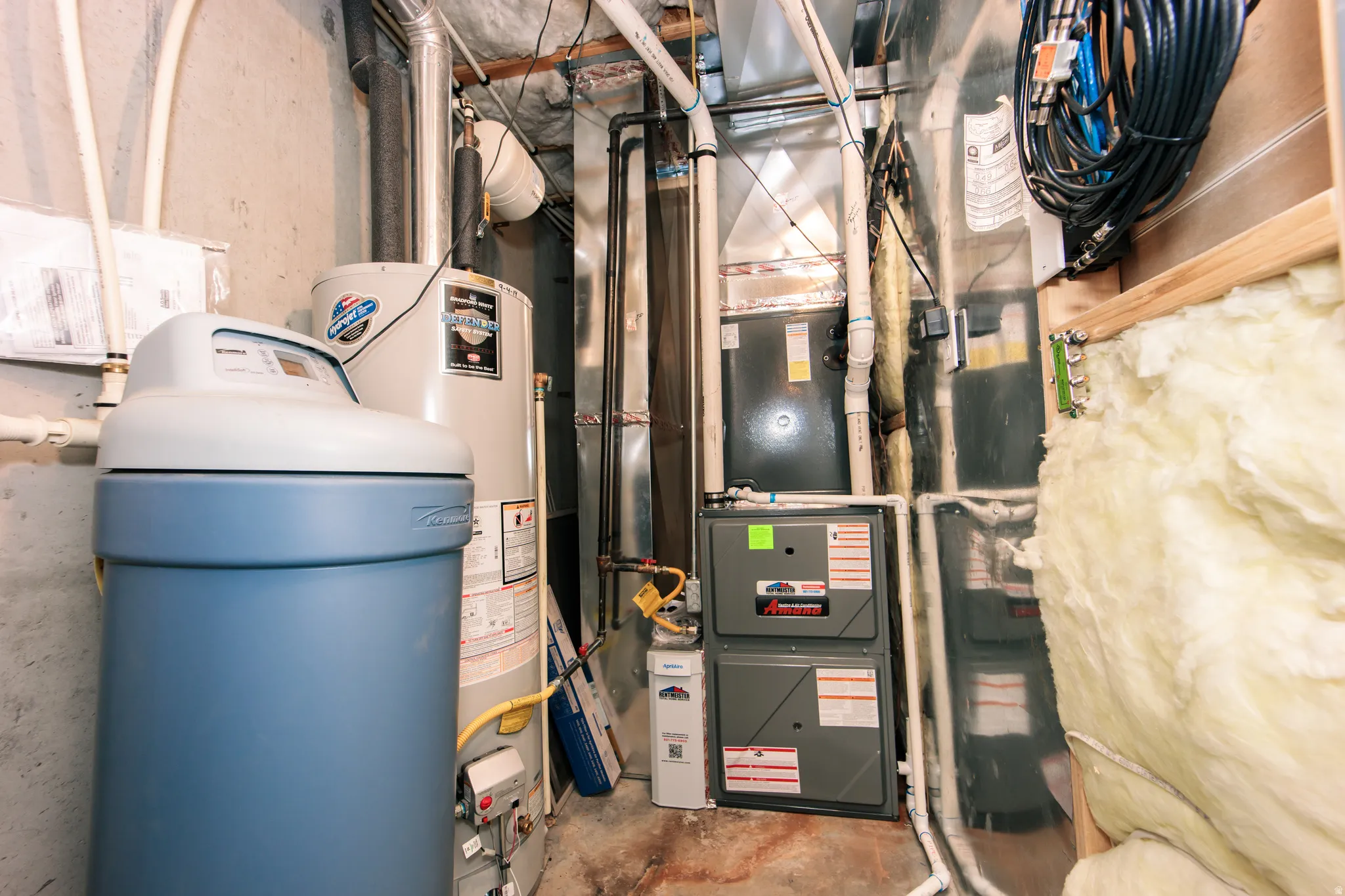 Utility area featuring a water softener, water heater, and multiple HVAC units