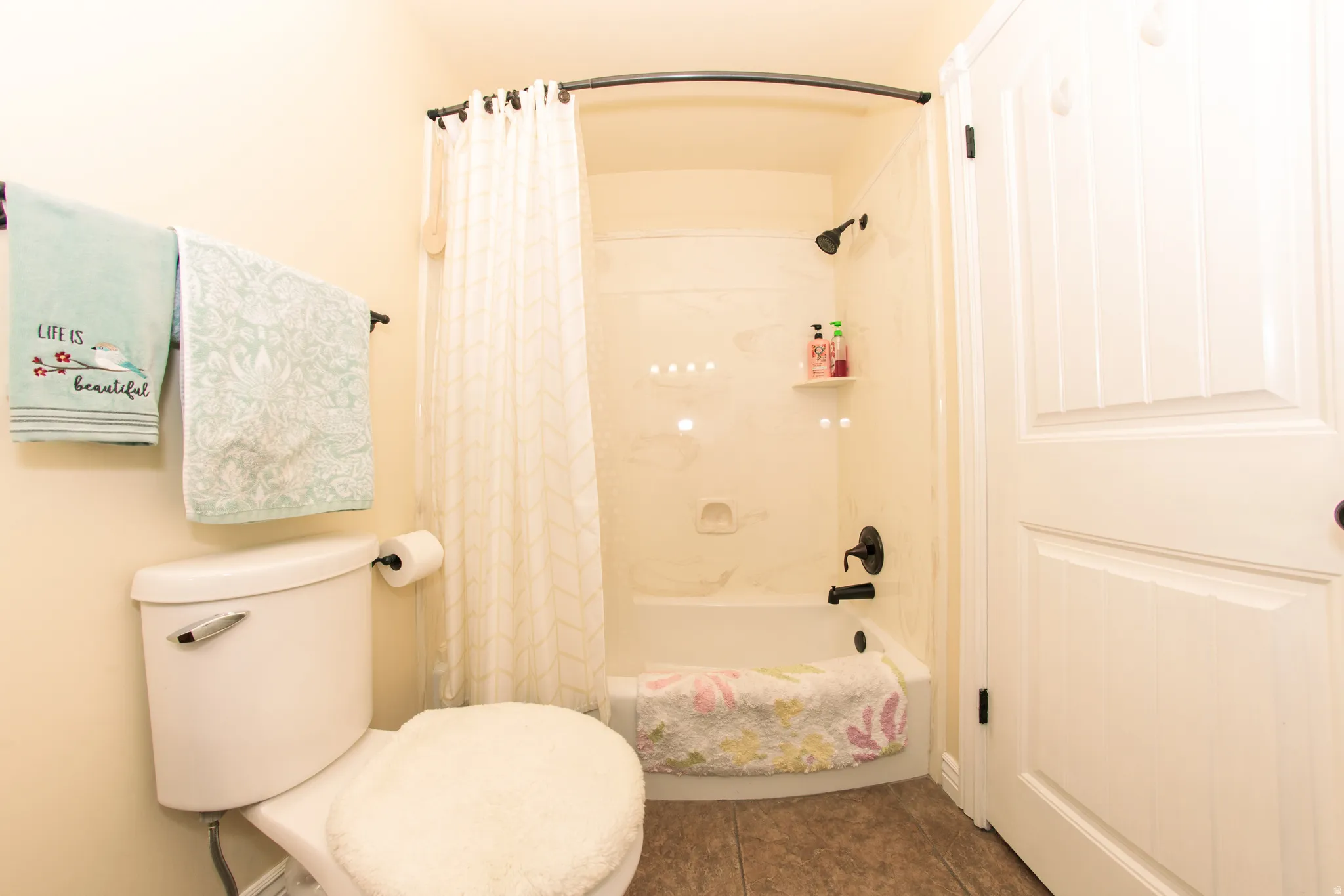 Bathroom with a shower-over-tub combination featuring dark-toned fixtures and a curved shower rod