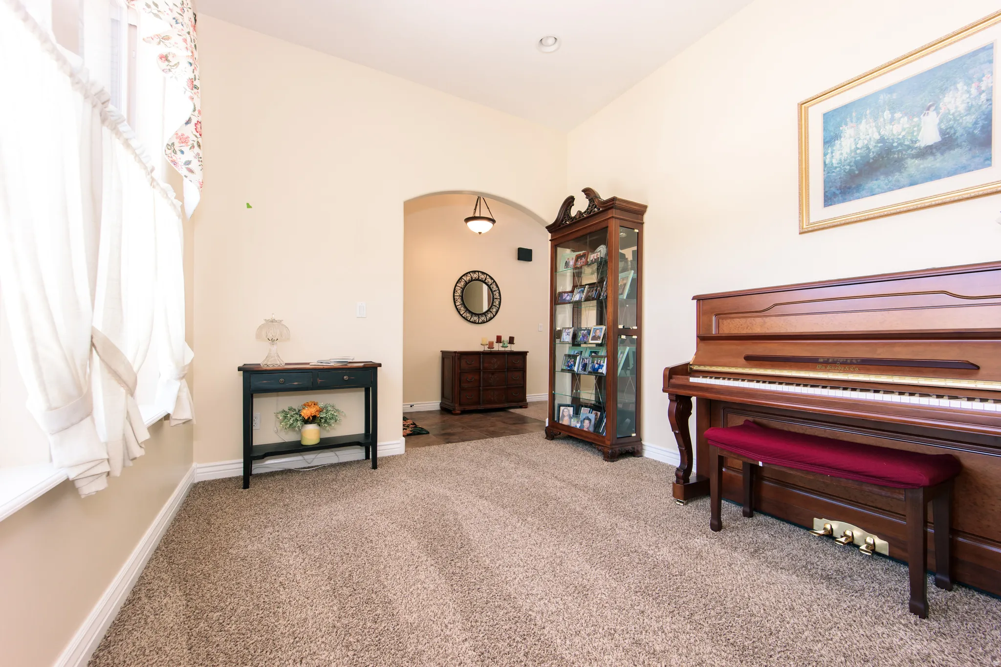 Carpeted interior space featuring a vaulted ceiling and a wide arched entryway. Could be used as a music room or office.