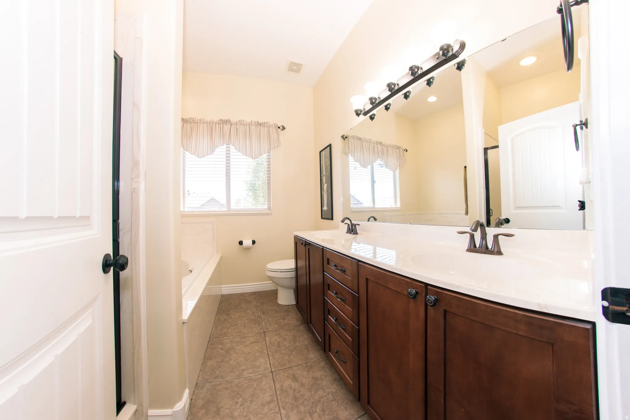 Master Bath, double vanity with integrated sinks and bronze-finish faucets, set against a large mirror with multi-bulb lighting