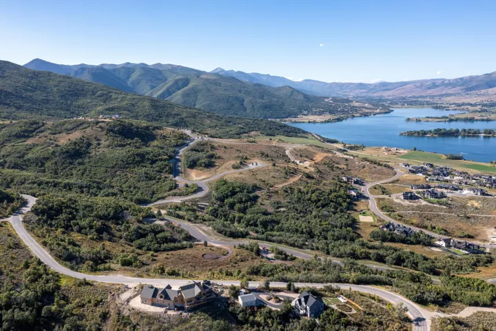 Expansive mountain landscape featuring a large body of water, several residential properties, and winding roads