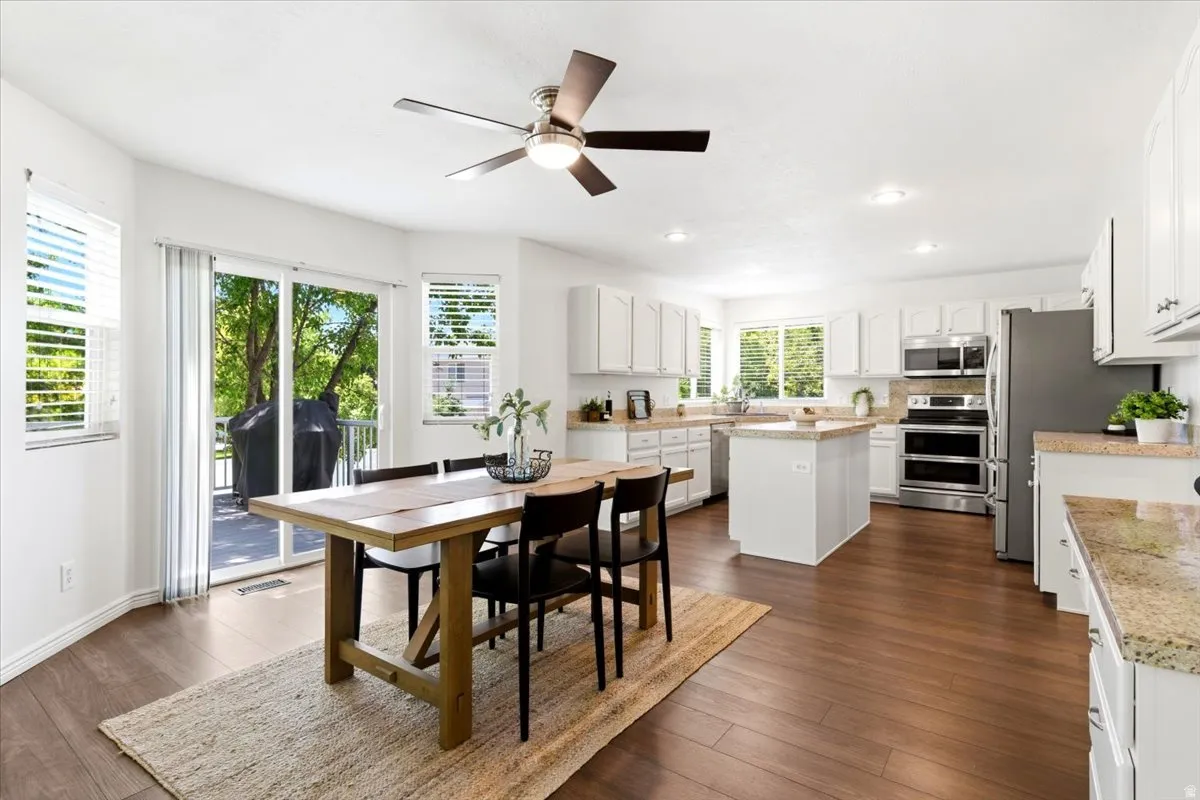 Open-concept kitchen and dining area featuring wood-finish flooring, white cabinetry, and light-toned countertops