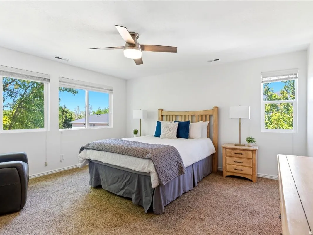 Bright bedroom featuring light-colored walls and soft carpet flooring