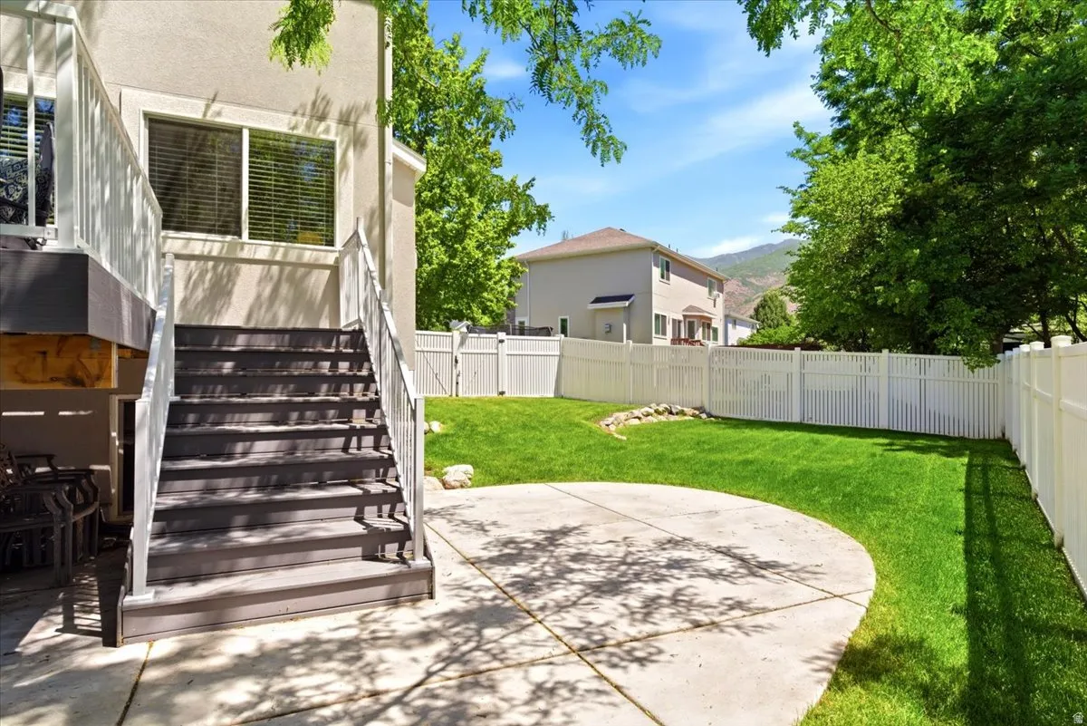 Expansive backyard featuring a manicured lawn, a large concrete patio, and a privacy fence