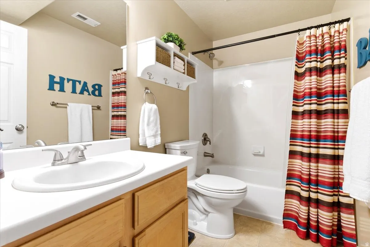 Bathroom featuring a single vanity with a white countertop and wood-finish cabinetry, an integrated sink with a chrome faucet, and a white tub/shower combination