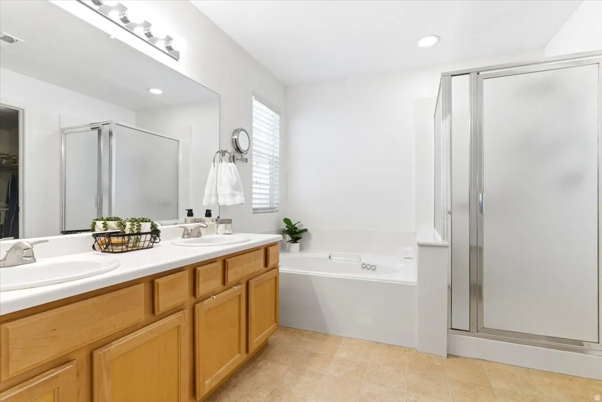 Bathroom featuring a dual-sink vanity with light wood cabinetry and a white countertop