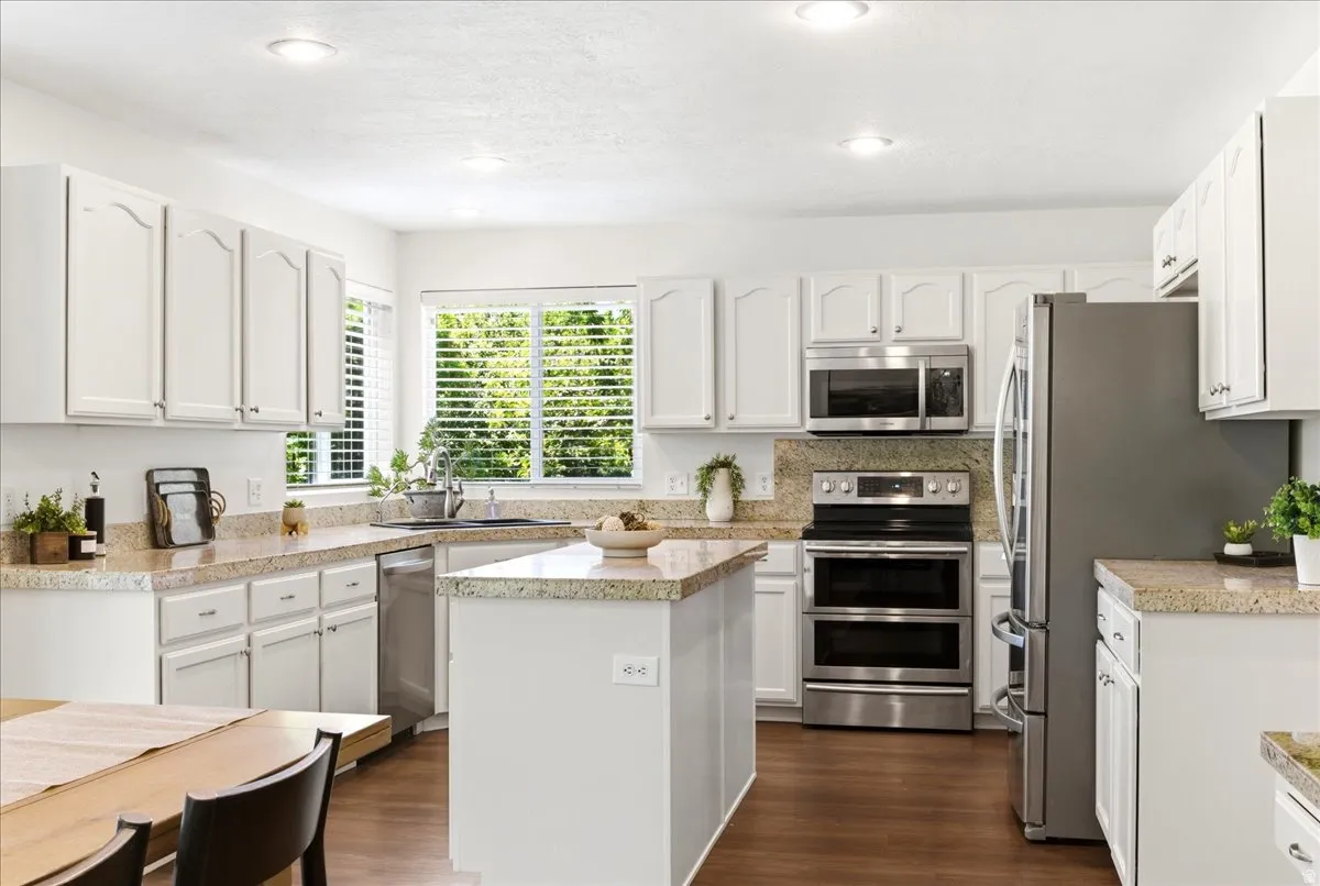 Bright kitchen featuring white cabinetry, light-toned countertops, a central island, stainless steel appliances, and recessed lighting